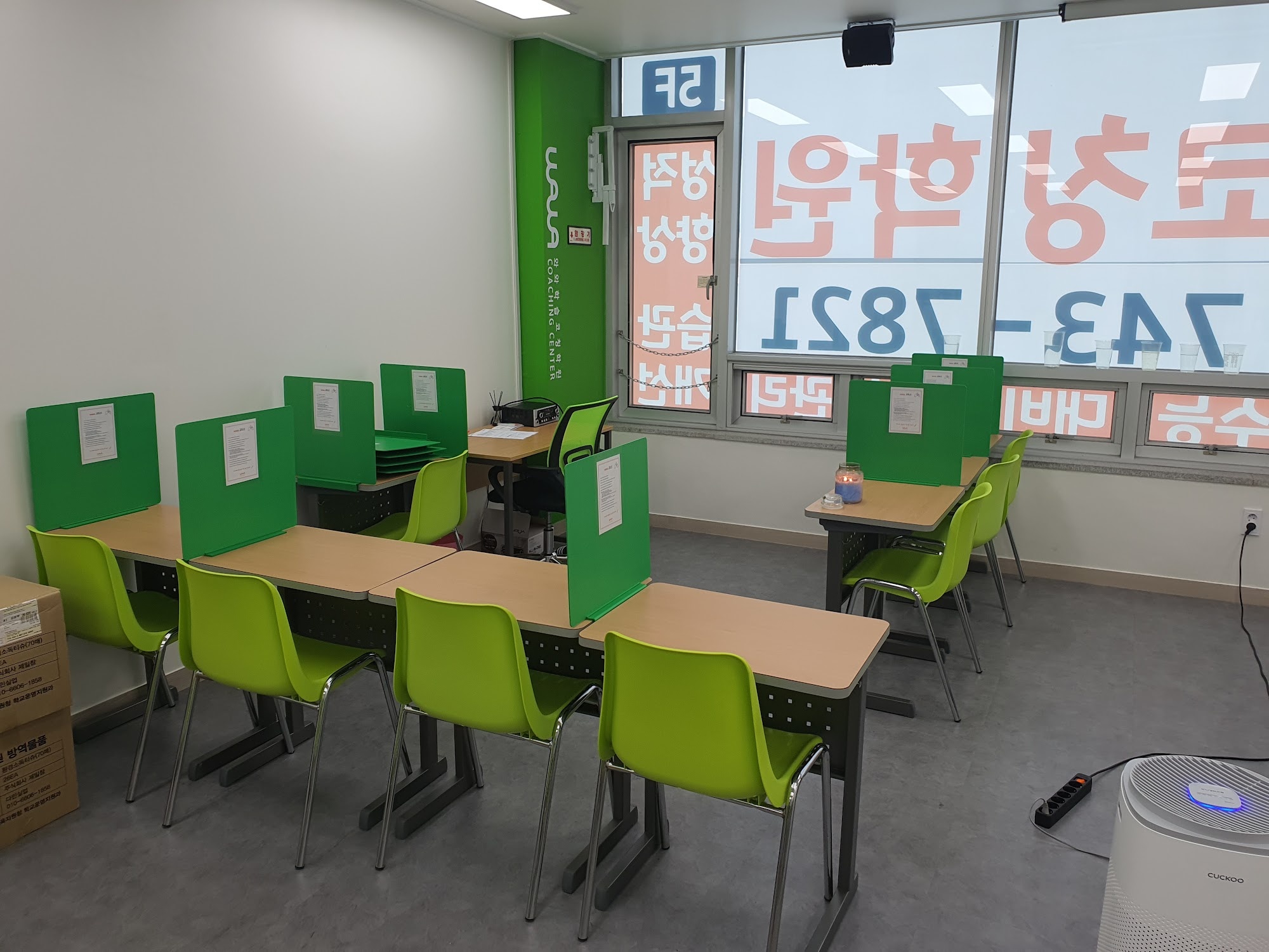 창원 진해구 석동 와와학습코칭 석동점 학습실 — 초록색 가림판이 세워진 개인 책상들과 초록 의자, 밝은 창가