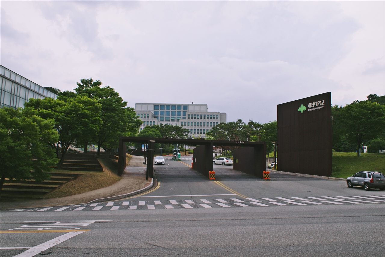 대전 동구 용운동 대전대학교 정문 — 갈색 철제 게이트와 대전대학교 표지석, 뒤로 보이는 캠퍼스 건물