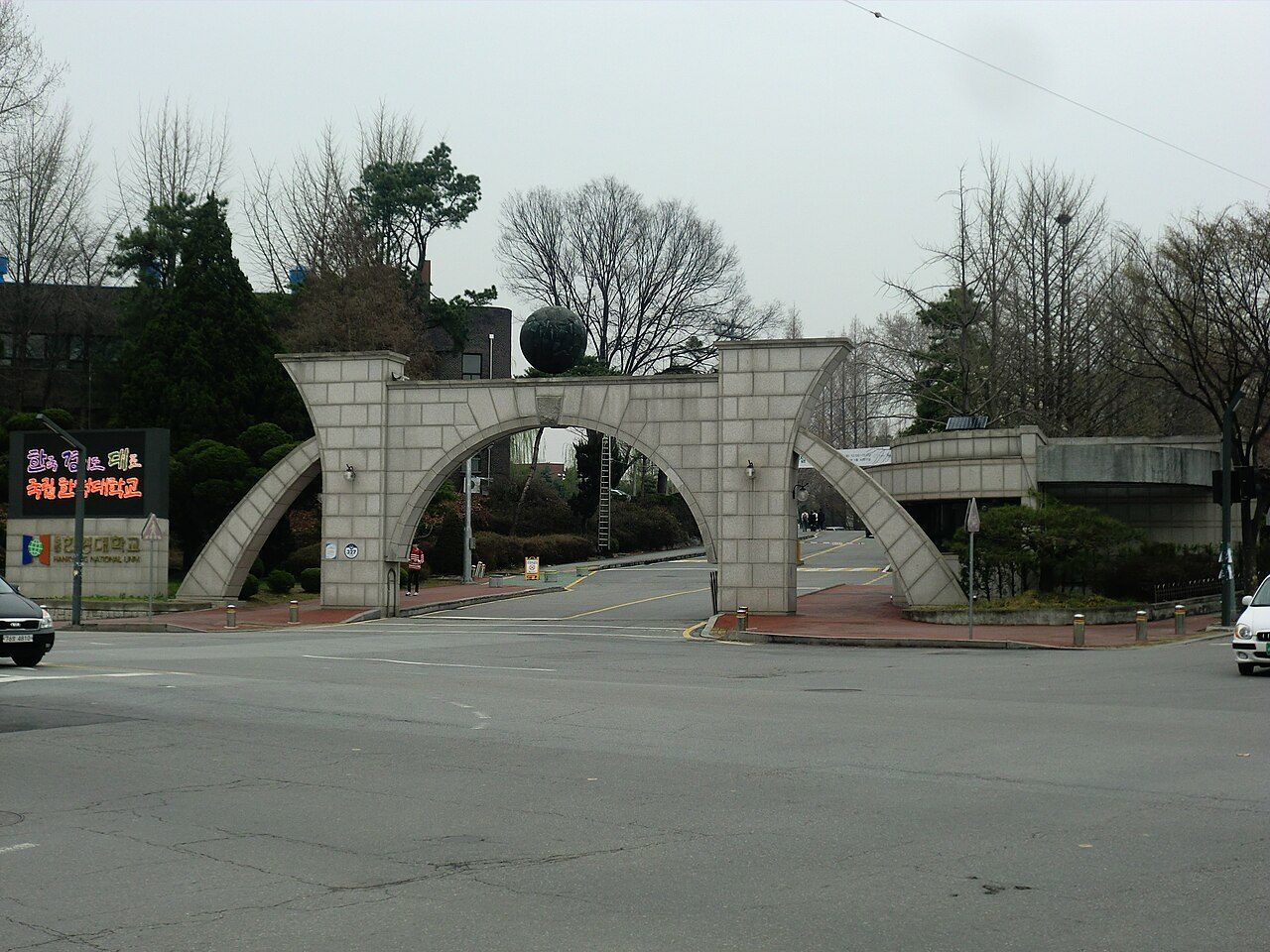 한경국립대학교 안성캠퍼스 정문 — 아치 모양의 돌문과 그 위에 놓인 조형물, 왼쪽에 학교 안내 전광판이 보이는 모습